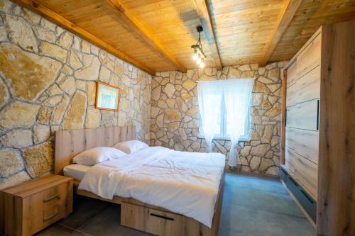 a bedroom with a bed and a stone wall at Kuca za odmor Sliskovic 