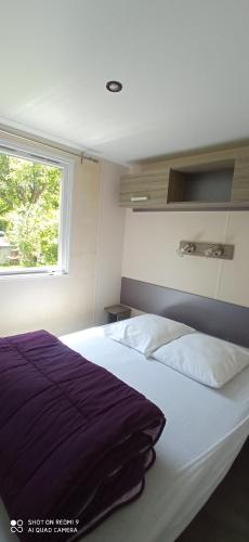 une chambre avec un grand lit blanc avec une fenêtre dans l'établissement Camping LE Moulin, à La Motte-Chalançon