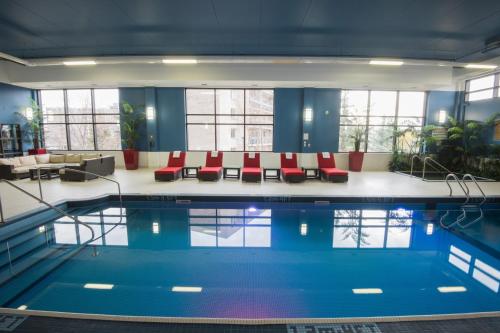 uma piscina com cadeiras vermelhas num quarto com janelas em Four Points by Sheraton Winnipeg South em Winnipeg