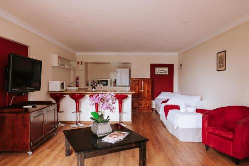 1 dormitorio con 1 cama y cocina con silla roja en Floreal House, en Ciudad del Cabo