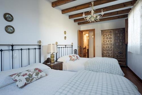 a bedroom with two beds and a chandelier at Casa Rural Martínez in Peñacoba