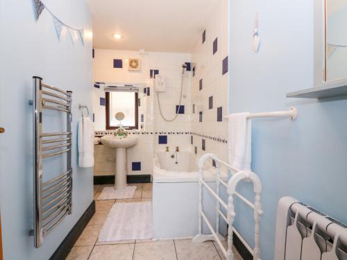 a white bathroom with a sink and a tub at Lobster Pot Cottage in Banff