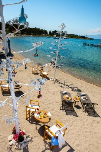 a beach with chairs and tables and a body of water at Mark Warner Phokaia Beach Resort in Foca