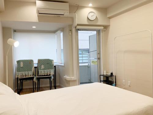 a bedroom with a bed and two chairs and a clock at Ikebukuro Center! Ikebukuro 5min walk! 池袋中心地带! 池袋车站步行5分! 公寓干湿分离! 智能马桶! 高速无限制网路!804 in Tokyo