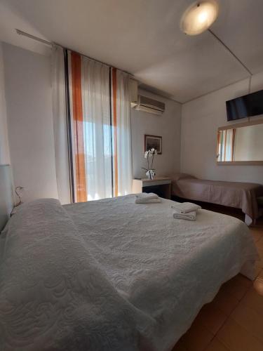 a bedroom with a large white bed and a window at Hotel San Domingo in Lido di Camaiore
