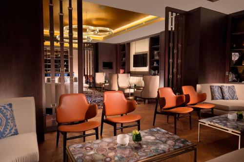a lobby with orange chairs and tables in a room at The St. Regis Astana in Astana