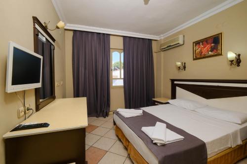 Habitación de hotel con cama y escritorio con TV. en Club Selen icmeler, en Marmaris