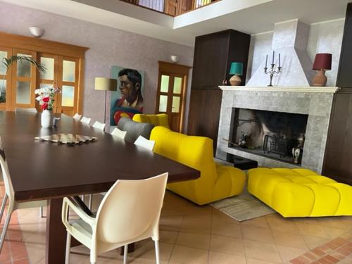 een woonkamer met een tafel en gele stoelen en een open haard bij VALLELY la collina sul mare B&B d'Abruzzo in Francavilla al Mare