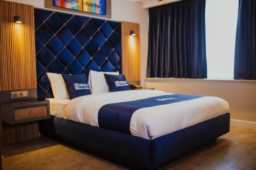 a bedroom with a large bed with a blue headboard at QUALA HOTELS & LOUNGE in Aksaray