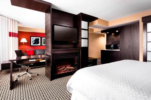 Habitación de hotel con cama, escritorio y TV. en Four Points by Sheraton Mississauga Meadowvale, en Mississauga