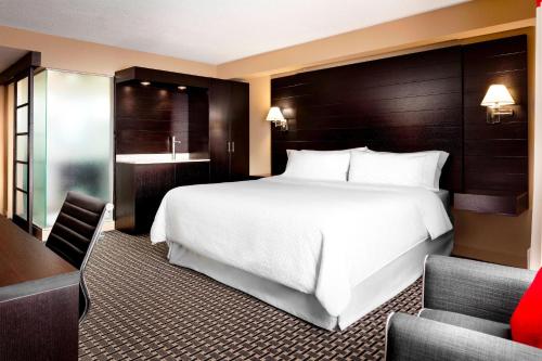 a hotel room with a white bed and a desk at Four Points by Sheraton Mississauga Meadowvale in Mississauga