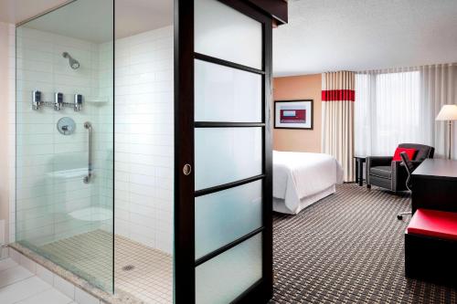 una habitación de hotel con ducha y un dormitorio en Four Points by Sheraton Mississauga Meadowvale en Mississauga