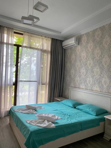 Schlafzimmer mit einem Bett mit blauer Bettwäsche und einem Fenster in der Unterkunft House on Moryakov 55 in Chakvi