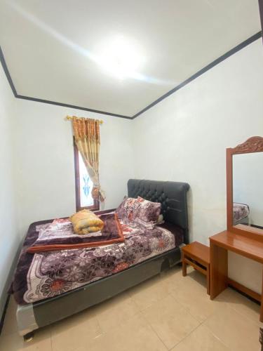 DiyengにあるHomestay Ulya 2の窓と鏡付きの部屋のベッド1台分です。
