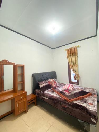Schlafzimmer mit einem Bett, einer Kommode und einem Spiegel in der Unterkunft Homestay Ulya 2 in Diyeng