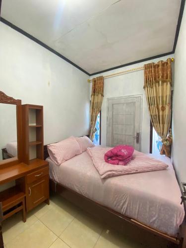 a bedroom with two beds with pink sheets and a mirror at Homestay Ulya 2 in Diyeng