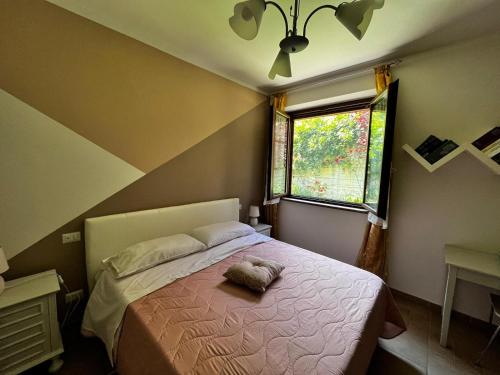 um quarto com uma cama com um cobertor rosa e uma janela em Nonna Lella - Appartamento con parcheggio privato em Montepulciano
