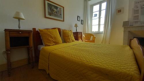 a bedroom with a yellow bed and a window at Maison Rives - Village du Livre de Montolieu in Montolieu