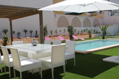 a white table and chairs with an umbrella and a pool at Can Mossènyer in San Antonio