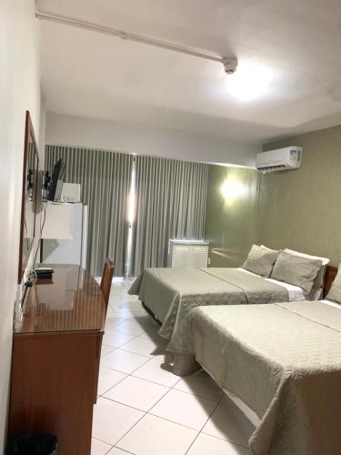 a hotel room with two beds and a television at Flat Centro de Brasília - Garvey Park Hotel in Brasilia