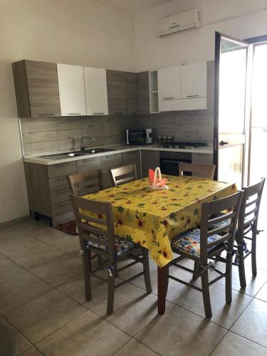 a kitchen with a table with a yellow table cloth at White House in Tre Fontane