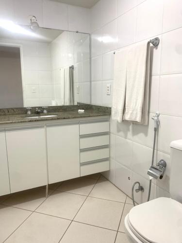 a bathroom with a toilet and a sink and a mirror at Flat Centro de Brasília - Garvey Park Hotel in Brasilia