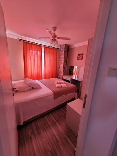 a small bedroom with a bed and a ceiling fan at Apsa Butik Hotel in Sukhum