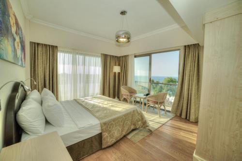 a hotel room with a bed and a table and a balcony at Jasmine Court Hotel & Casino in Kérynia