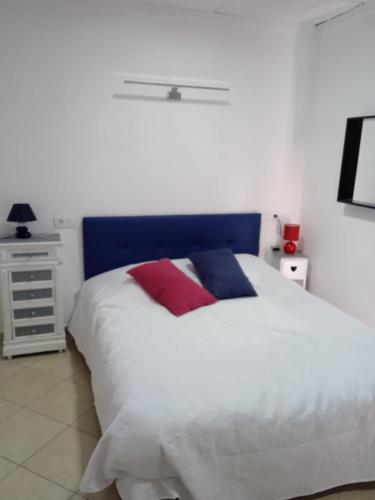 Un dormitorio con una cama blanca con almohadas rojas y azules en La Rana Azul en Vélez