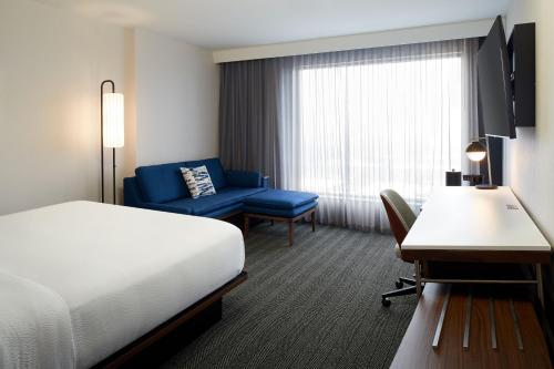 a hotel room with a bed and a chair and a desk at Courtyard by Marriott Montreal Midtown in Montréal