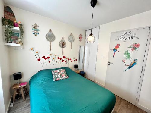 Un dormitorio con una cama verde con pájaros y flores en la pared en Le Mini Nid by LPNL, en Rives