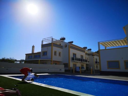 a man standing next to a swimming pool next to a house at Apartamento Sol e Mar in Vila Nova De Cacela