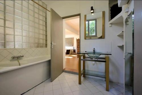 une salle de bain avec une baignoire, un lavabo et un miroir dans l'établissement Les Gîtes de la Madrague, à Ensuès-la-Redonne