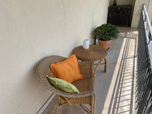 a wicker chair with an orange pillow and a table at i pennacchi in Catania