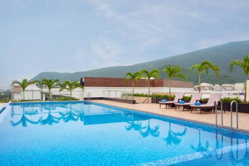 uma piscina com palmeiras e uma montanha ao fundo em Fairfield by Marriott Visakhapatnam em Visakhapatnam