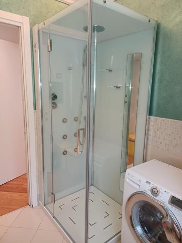 a glass shower in a laundry room with a washing machine at Savoia Terrace with Mountain View in Taceno
