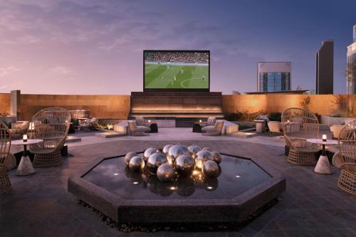 a rooftop patio with a television and tables and chairs at JW Marriott Hotel Riyadh in Riyadh
