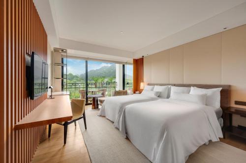 a hotel room with two beds and a television at The Westin Tashee Resort, Taoyuan in Daxi