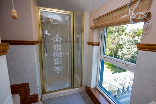 La salle de bains est pourvue d'une douche et d'une fenêtre. dans l'établissement 5 Bedroom Holiday Home With Spa Now Available, à Tenby