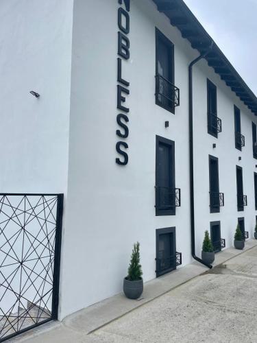 a white building with a sign on the side of it at Pensiunea Nobless Eșelnița in Eşelniţa