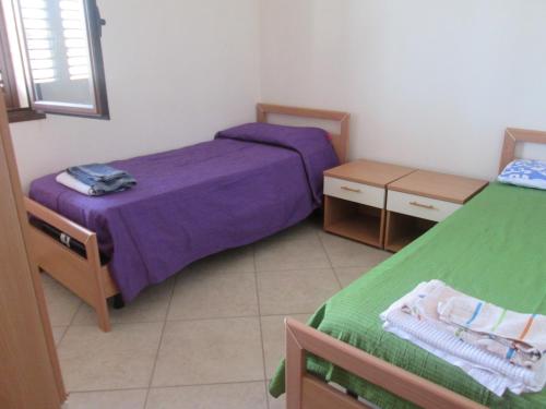 a bedroom with two beds with purple sheets at White House in Tre Fontane