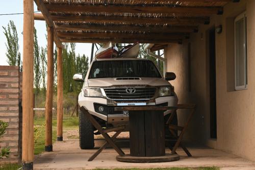 a white suv parked under a wooden structure at Cabañas Viento Andino in San Rafael