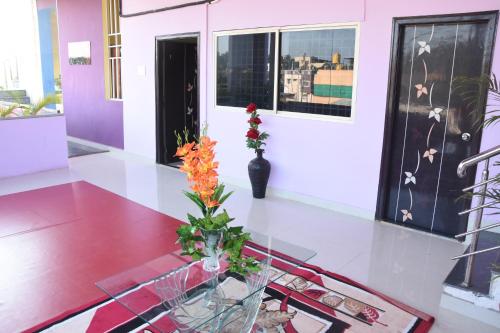 a room with a table with a vase with flowers on it at H P HomeStay in Dhārwād