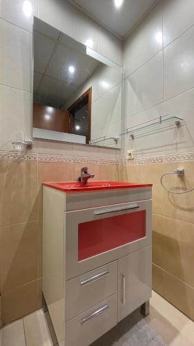 a bathroom with a red sink and a mirror at Work and Rest Away From Home in Paterna