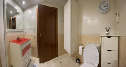 a bathroom with a toilet and a sink and a clock at Work and Rest Away From Home in Paterna