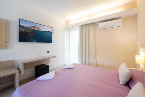 a hotel room with a pink bed and a window at Terinikos Sunny Garden Hotel & Junior Suites New Renovation 2025 in Ialyssos