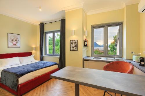 a bedroom with a bed and a desk and windows at Leopoldo in Baveno
