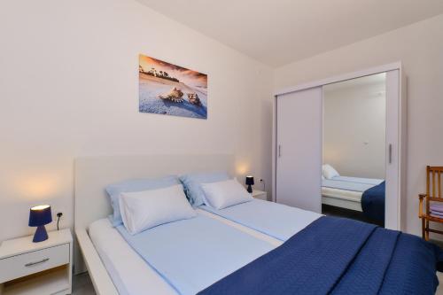 a bedroom with a large bed and a mirror at Apartmani Raić in Mali Lošinj