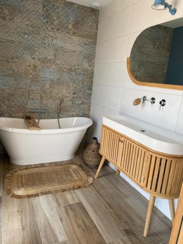La salle de bains est pourvue d'une baignoire, d'un lavabo et d'un miroir. dans l'établissement Villa contemporaine La Rochelle, à La Genilliere