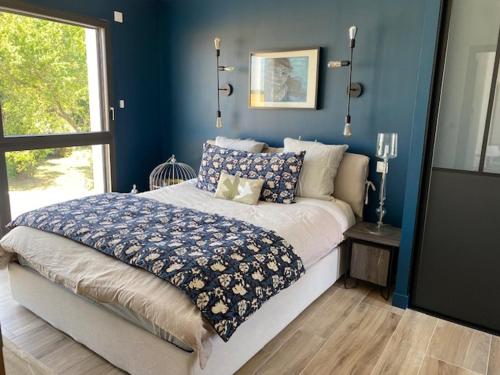 - une chambre avec un lit aux murs bleus et une fenêtre dans l'établissement Villa contemporaine La Rochelle, à La Genilliere
